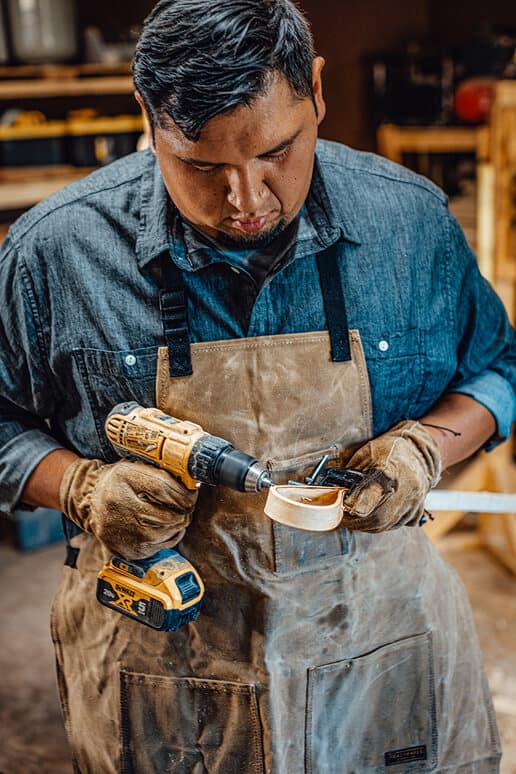 Brenner Billy drills a hole into the frame of a stickball stick