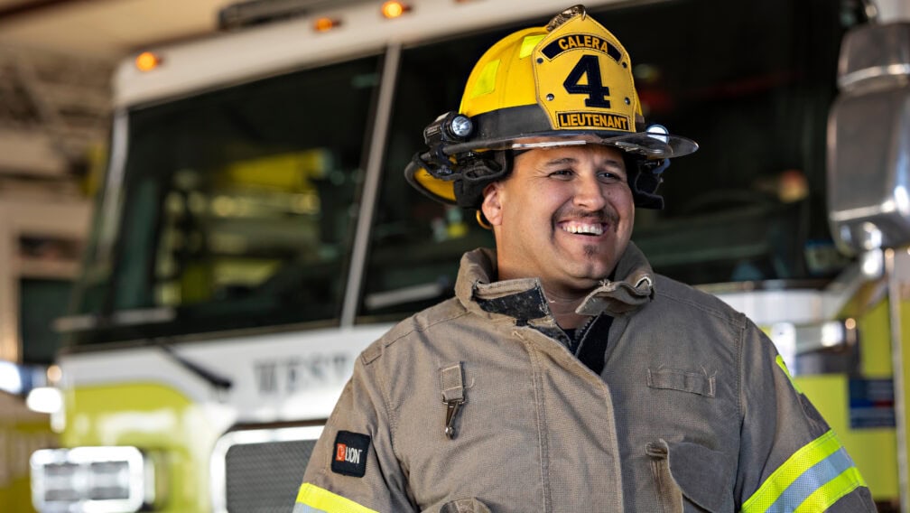 Jake Trujillo smiles in front of a fire truck