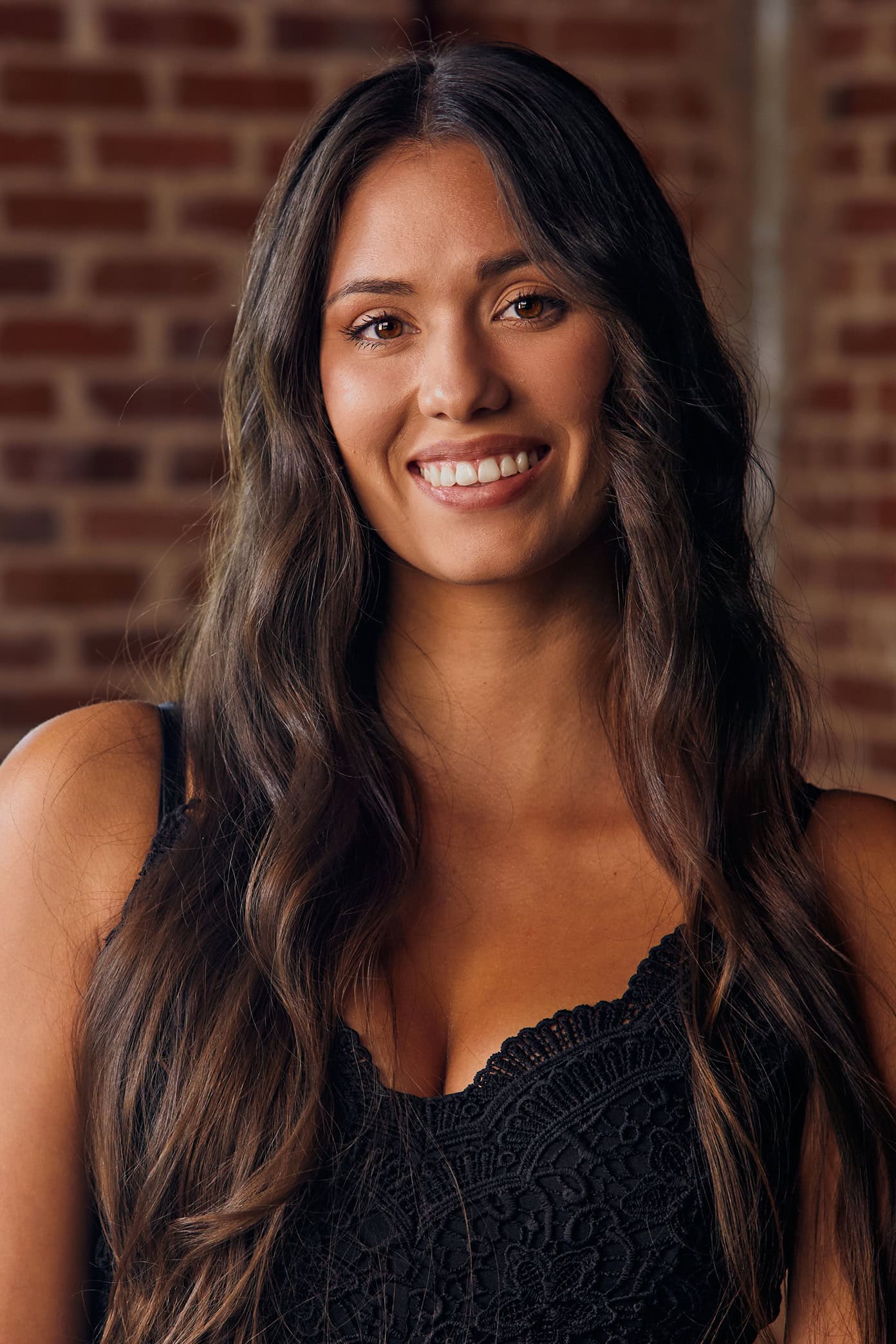 Jula Harjo smiles in front of a brick wall
