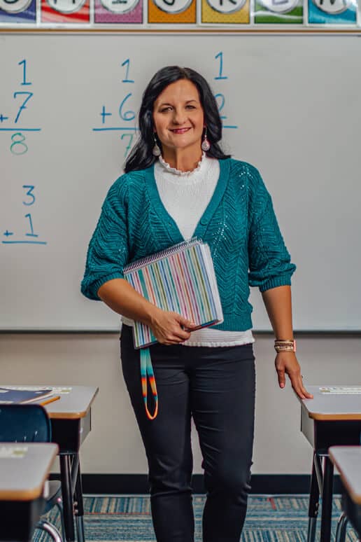 Stephanie Roberts in her classroom carrying her notebook.
