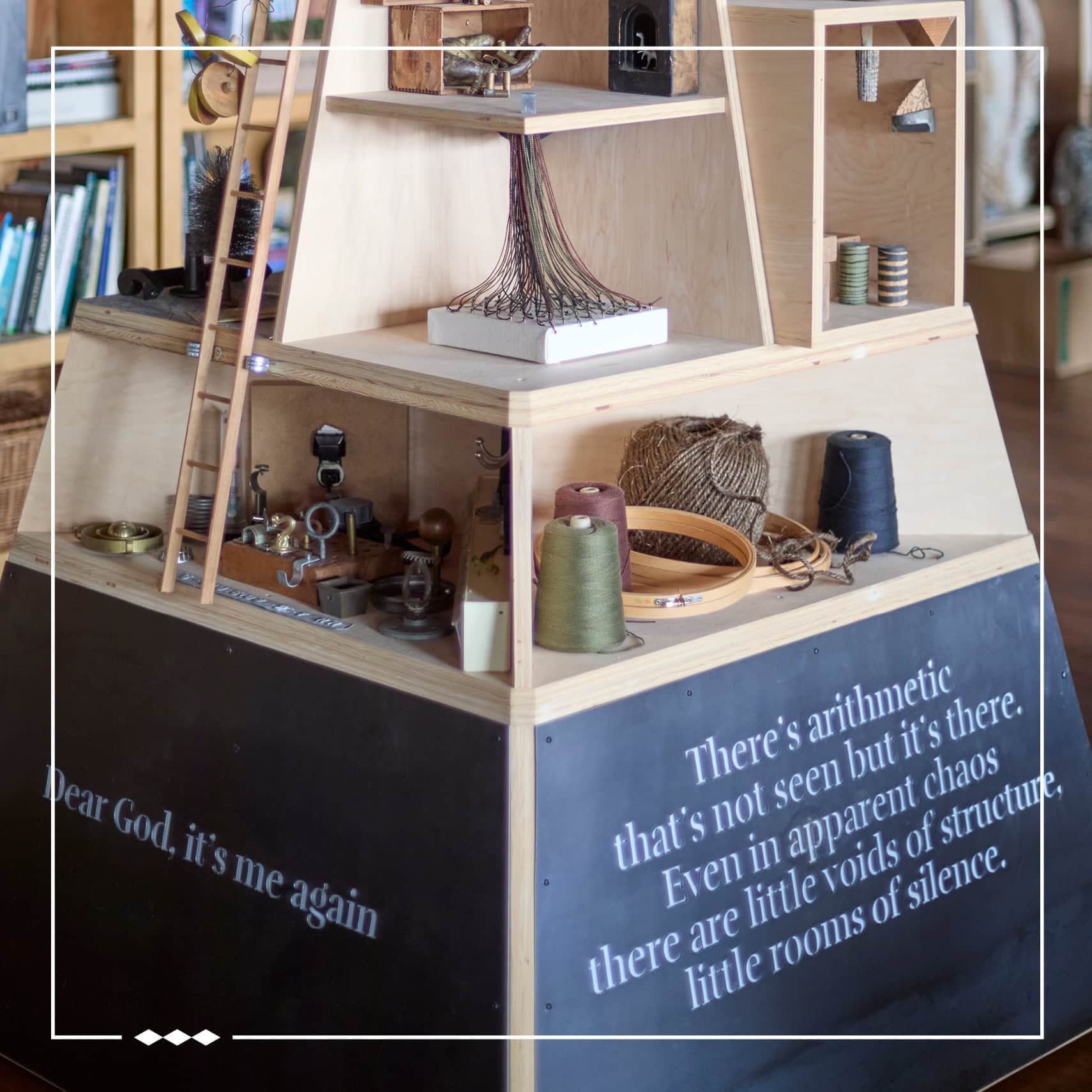 A pyramid-shaped bookshelf with custom quotes on along its base