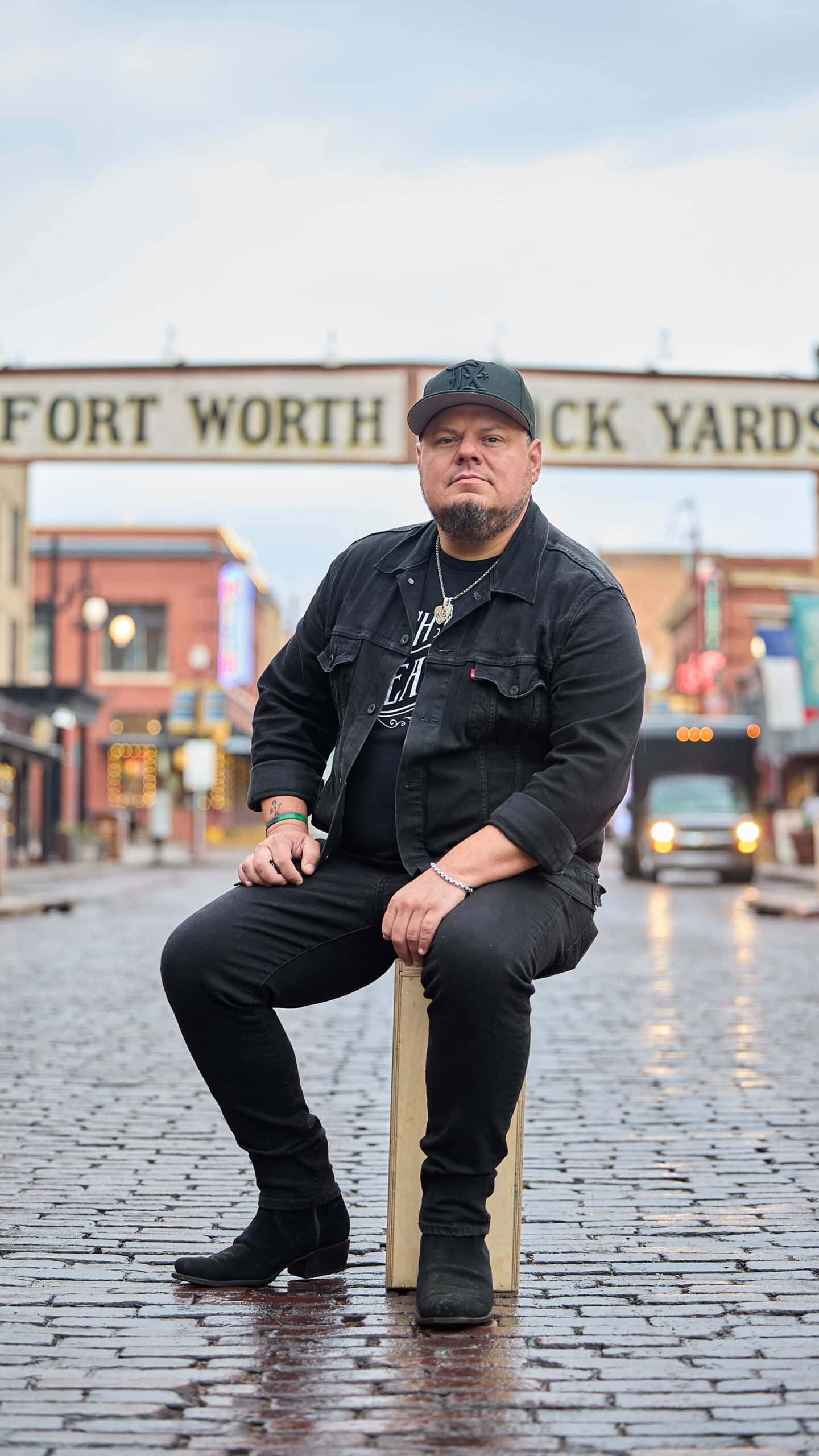 Joey Green sitting in front of Fort Worth Stockyards.